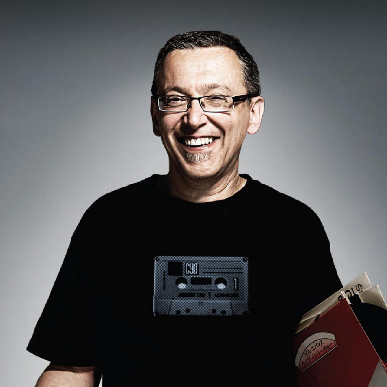 Radio producer and host Nou Dadoun smiling and carrying vinyl under his arm